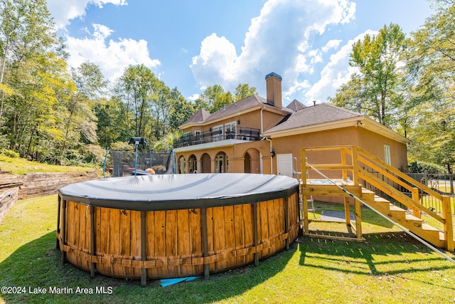 exterior space with a lawn, a balcony, and a hot tub