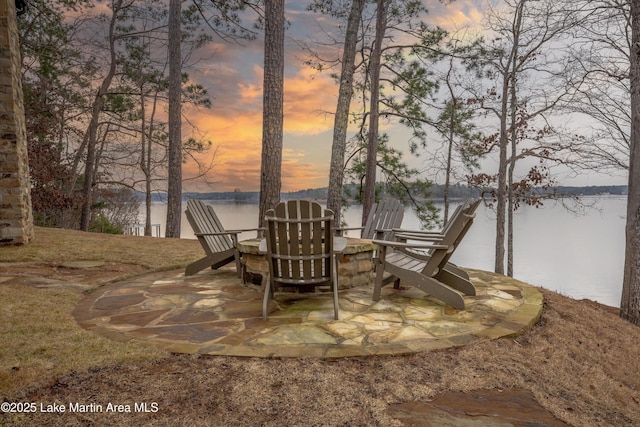 patio terrace at dusk featuring a water view