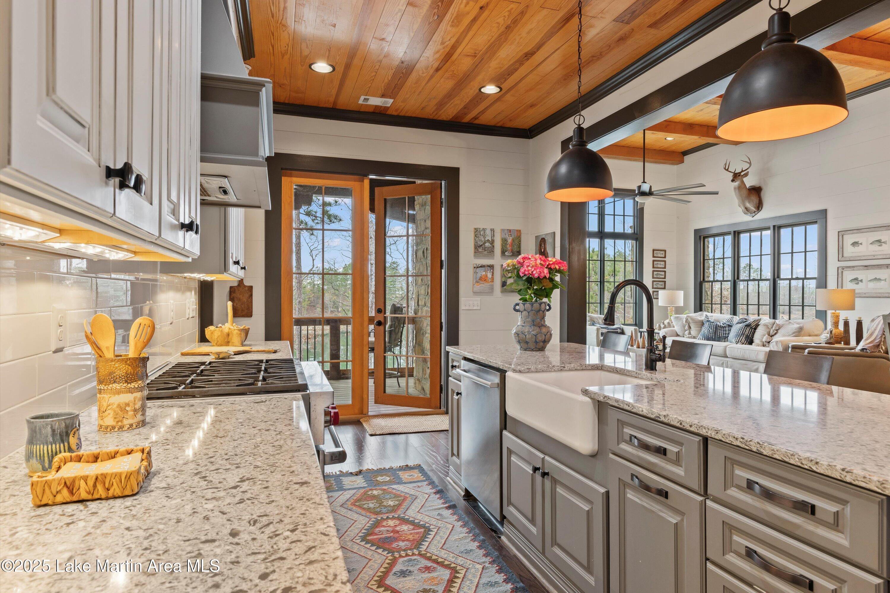 kitchen with sink, light stone counters, wooden ceiling, stainless steel dishwasher, and pendant lighting