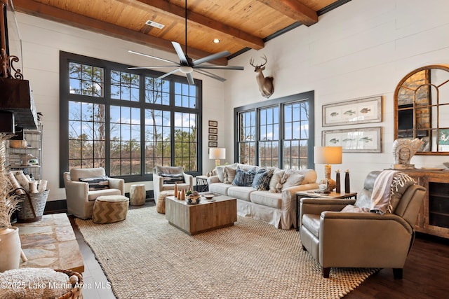 living room with wood-type flooring, wooden ceiling, ceiling fan, beamed ceiling, and a towering ceiling