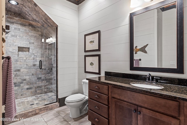 bathroom with vanity, wood walls, toilet, and walk in shower