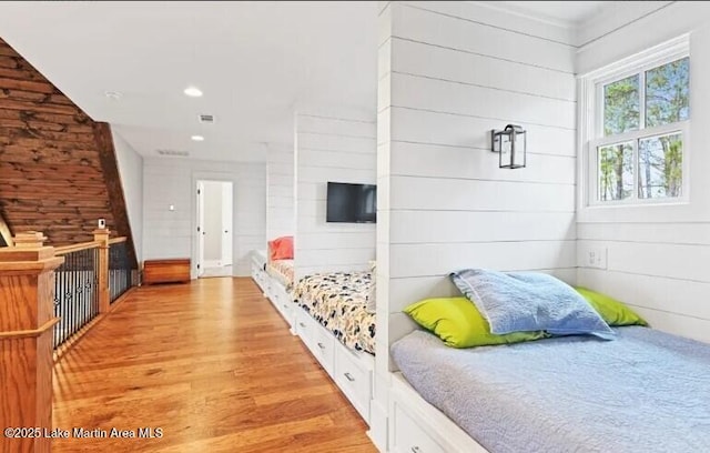 bedroom with wood walls and light wood-type flooring