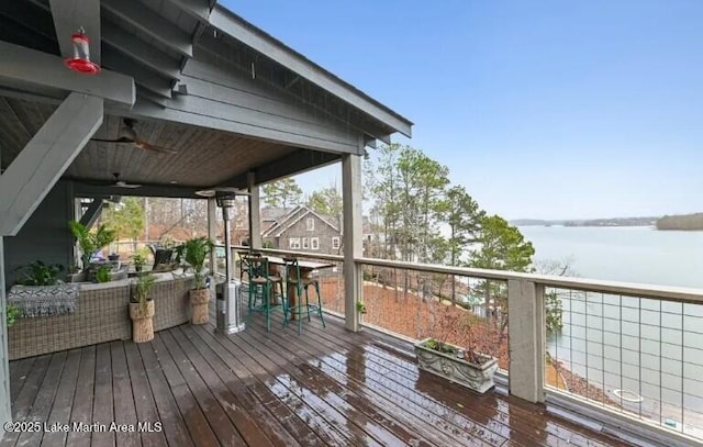 deck with ceiling fan and a water view