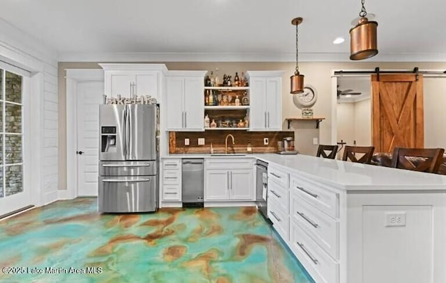 kitchen with pendant lighting, sink, appliances with stainless steel finishes, white cabinets, and a barn door