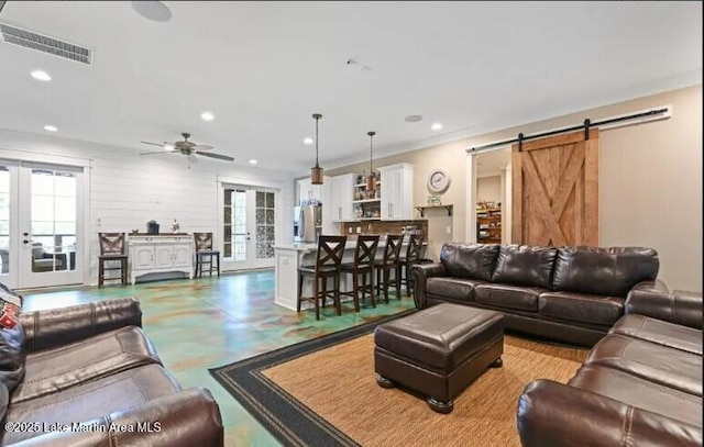 living room featuring a barn door, plenty of natural light, ceiling fan, and french doors