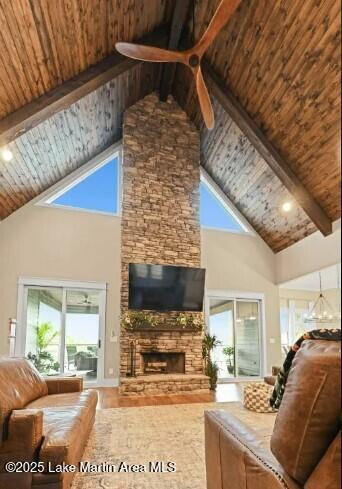 living room with a stone fireplace, a healthy amount of sunlight, wooden ceiling, and beam ceiling