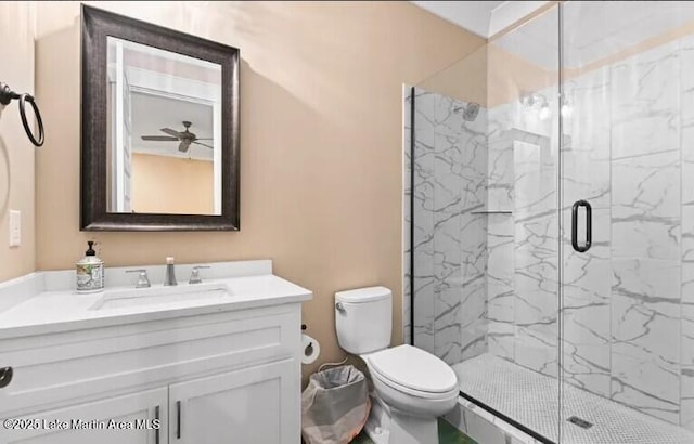 bathroom with vanity, ceiling fan, a shower with shower door, and toilet