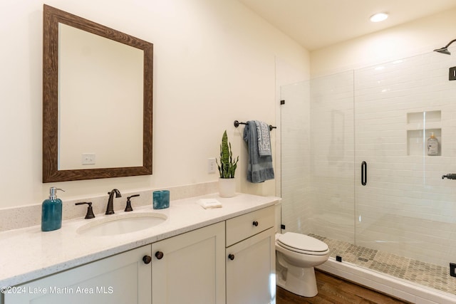 bathroom featuring hardwood / wood-style flooring, vanity, toilet, and a shower with door