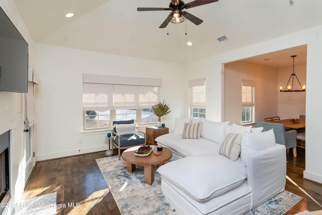 living room featuring dark wood-type flooring, a healthy amount of sunlight, and ceiling fan with notable chandelier