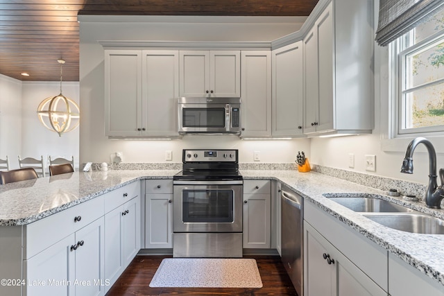 kitchen with appliances with stainless steel finishes, dark hardwood / wood-style flooring, light stone counters, and sink