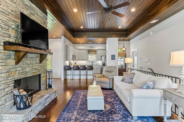 living room with ceiling fan, sink, dark hardwood / wood-style flooring, a fireplace, and wood ceiling