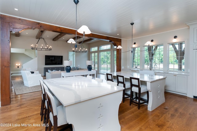 kitchen with a spacious island, hardwood / wood-style flooring, hanging light fixtures, and white cabinets