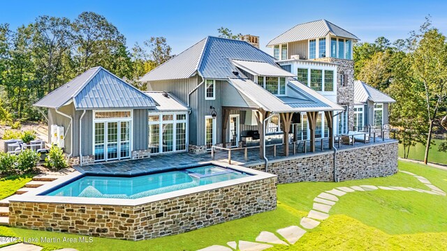 back of house featuring a swimming pool with hot tub, a yard, and a patio area