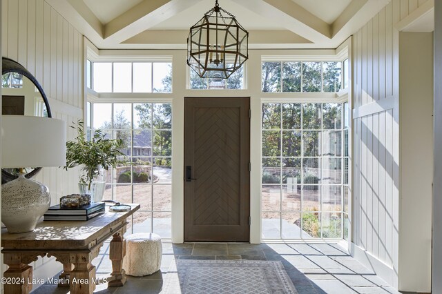 entryway featuring an inviting chandelier, wooden walls, and a high ceiling