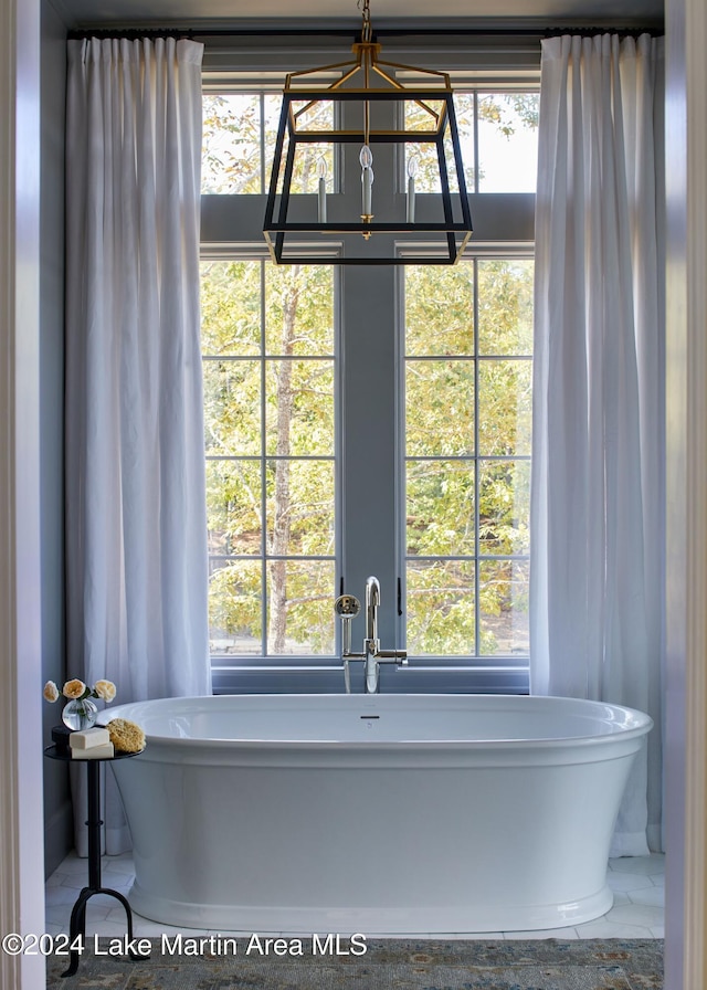 bathroom with an inviting chandelier, a bathing tub, and a wealth of natural light