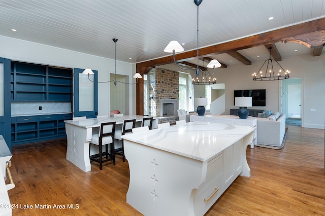 kitchen featuring pendant lighting, a breakfast bar area, a spacious island, a fireplace, and decorative backsplash