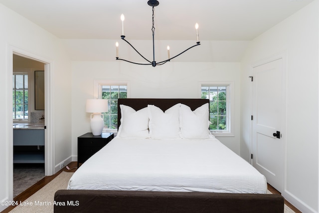 bedroom featuring ensuite bathroom and dark hardwood / wood-style flooring