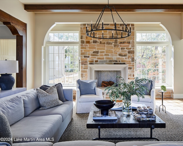 living room with a notable chandelier, a wealth of natural light, a fireplace, and beamed ceiling