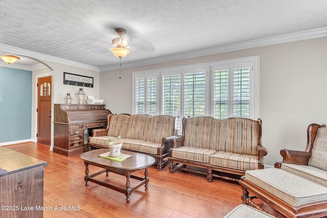 207 Mcdonald St, Dadeville, AL 36853 - living room featuring light wood-style flooring, ornamental molding, a ceiling fan, arched walkways, and a textured ceiling