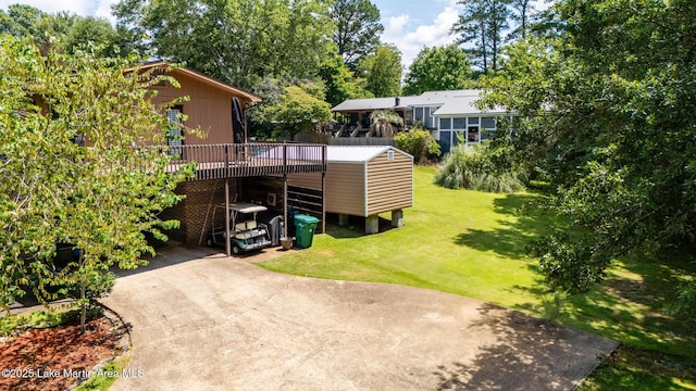 207 Mcdonald St, Dadeville, AL 36853 - view of grassy yard with concrete driveway, a deck, view of wooded area, and a carport