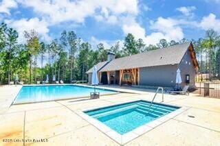 pool with fence, a community hot tub, and a patio area