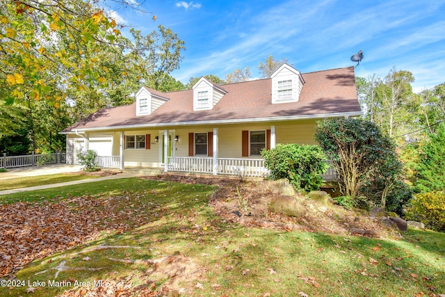 cape cod home with covered porch, a garage, and a front lawn