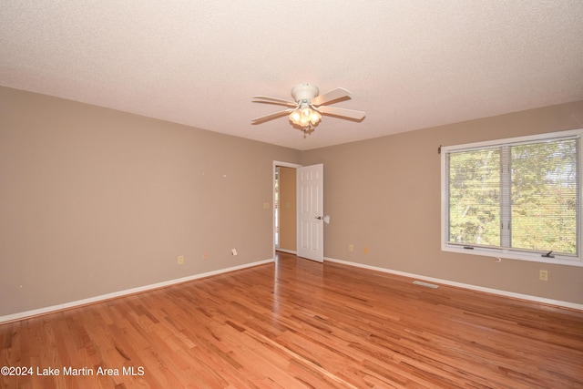 empty room featuring a textured ceiling, light hardwood / wood-style floors, and ceiling fan