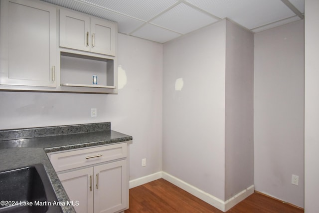 kitchen featuring white cabinetry, a drop ceiling, and dark wood-type flooring