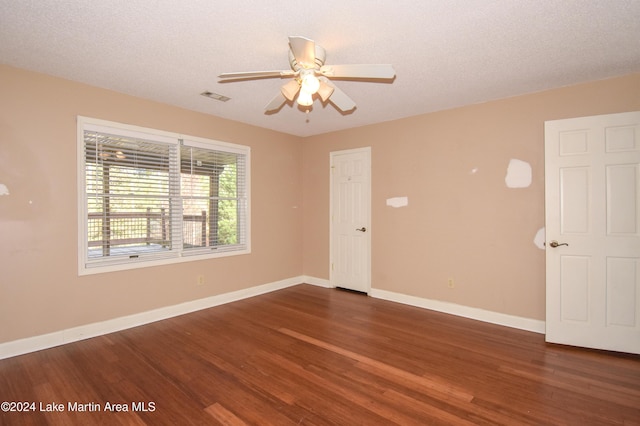 empty room featuring ceiling fan, dark wood-type flooring, and a textured ceiling