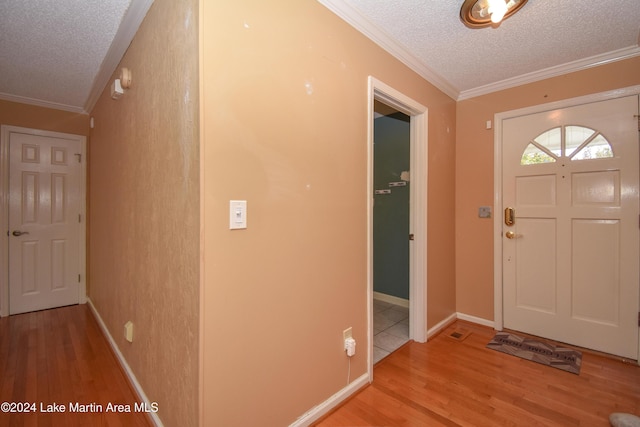 foyer featuring light hardwood / wood-style floors, a textured ceiling, and ornamental molding