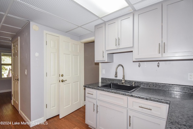 kitchen with hardwood / wood-style flooring, white cabinetry, and sink