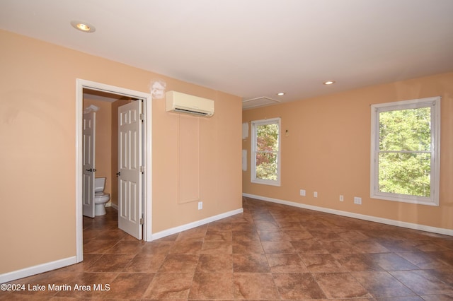 empty room featuring a wall mounted air conditioner and a wealth of natural light