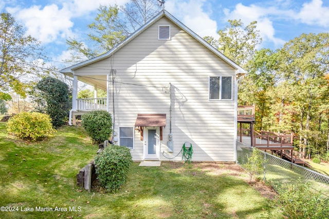 rear view of house featuring a lawn and a wooden deck