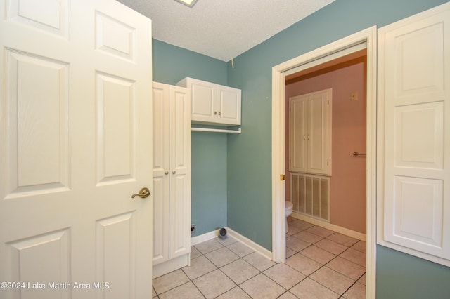 clothes washing area featuring light tile patterned floors and a textured ceiling