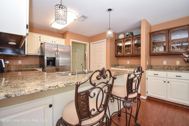 kitchen featuring pendant lighting, dark hardwood / wood-style floors, stainless steel fridge, and white cabinetry