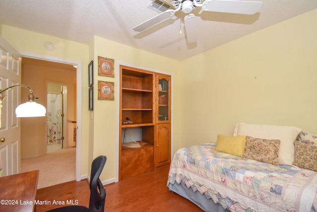 bedroom with hardwood / wood-style flooring, ceiling fan, and a textured ceiling