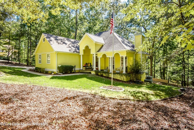 view of front of home with central air condition unit, a front lawn, and covered porch