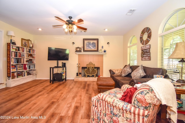 living room with hardwood / wood-style floors, ceiling fan, and a tile fireplace