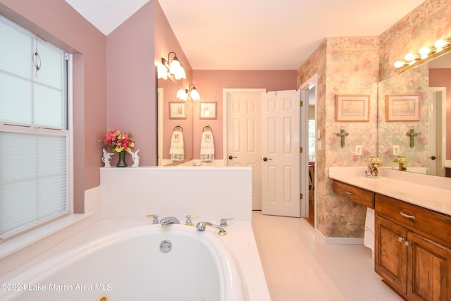 bathroom with tile patterned flooring, vanity, a relaxing tiled tub, and plenty of natural light