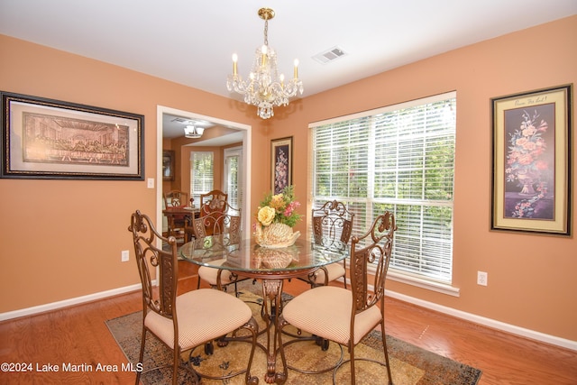 dining space with hardwood / wood-style floors and a notable chandelier