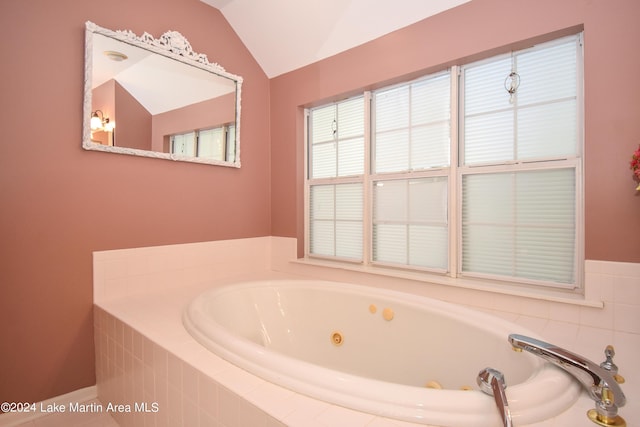 bathroom featuring lofted ceiling and tiled tub