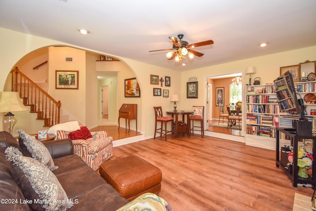 living room with wood-type flooring and ceiling fan with notable chandelier