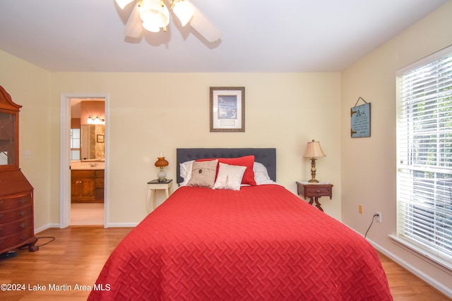 bedroom with light wood-type flooring, ceiling fan, and connected bathroom