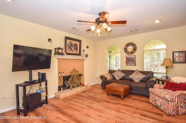 living room featuring a tile fireplace, ceiling fan, and hardwood / wood-style flooring