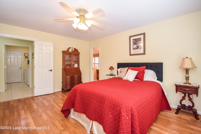 bedroom with hardwood / wood-style flooring, washer / clothes dryer, and ceiling fan