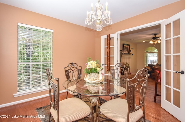 dining area with hardwood / wood-style flooring, ceiling fan with notable chandelier, and a healthy amount of sunlight