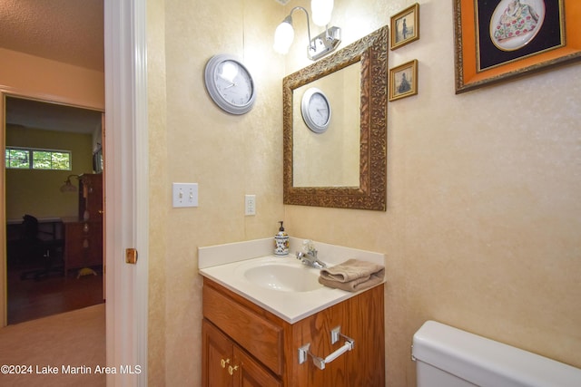 bathroom with vanity, a textured ceiling, and toilet