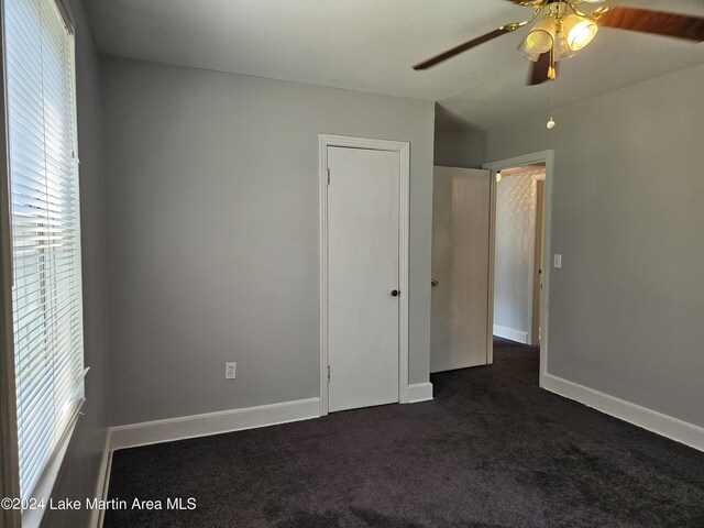 empty room featuring dark colored carpet and ceiling fan