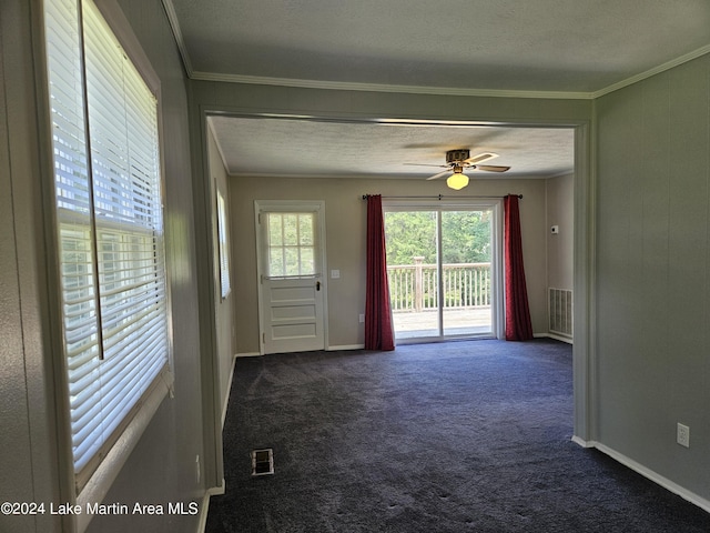 entryway featuring ceiling fan, crown molding, dark carpet, and a textured ceiling