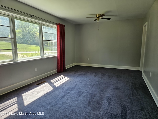 unfurnished room featuring ceiling fan and dark colored carpet